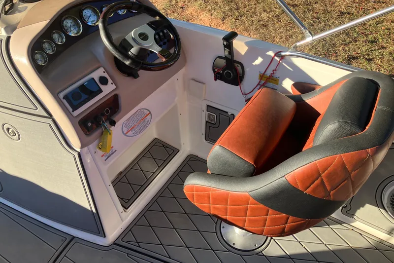 Slide: The Image of 2000 Chaparral Sunesta 232 boat cockpit with steering wheel and cushioned seat. - 11