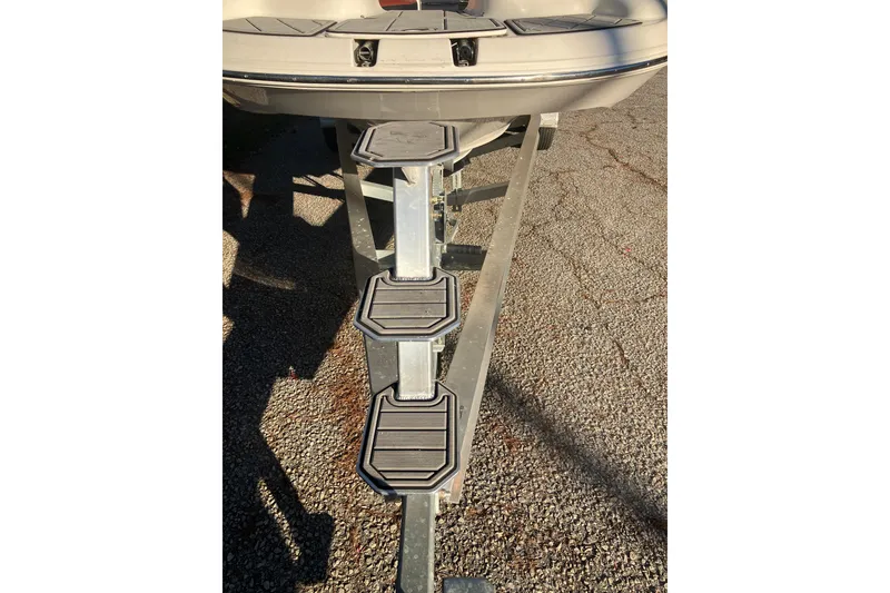 Slide: The Image of 2000 Chaparral Sunesta 232 boat trailer with metal steps on a gravel surface. - 26