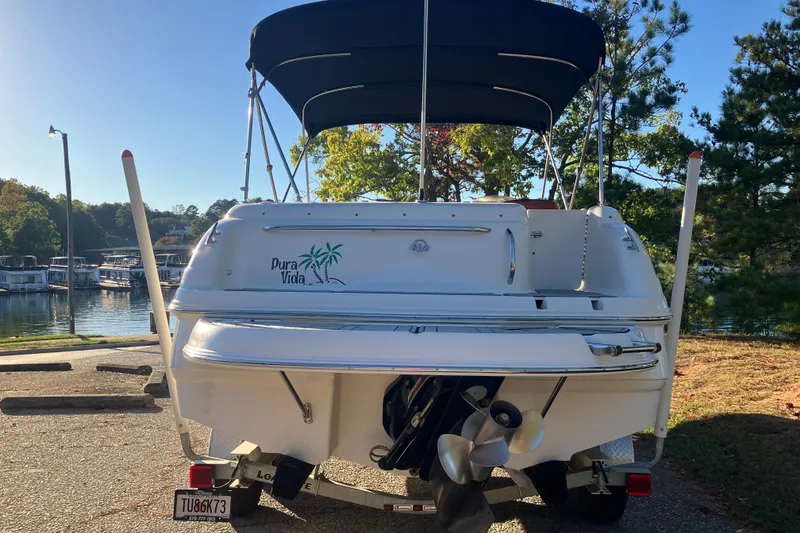 Slide: The Image of 2000 Chaparral Sunesta 232 boat with canopy, parked near a serene lakeside. - 5