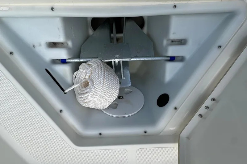 Slide: The Image of 2013 Skeeter SX240 boat anchor compartment with coiled rope and anchor. - 15