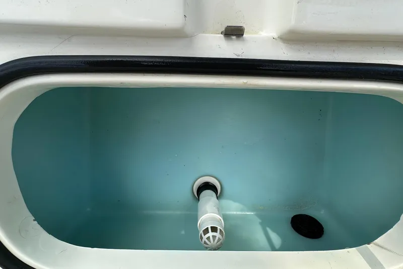 Slide: The Image of Livewell compartment in a 2013 Skeeter SX240 boat, featuring a drain and aerator. - 19