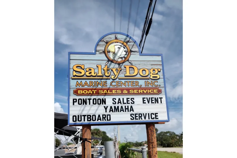 Slide: The Image of Salty Dog Marine Center sign advertising pontoon sales and Yamaha outboard service, under blue sky. - 15