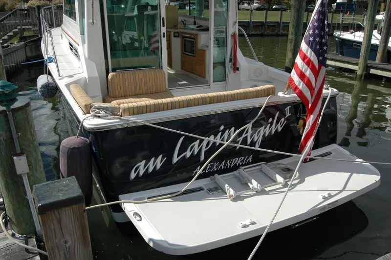 Slide: The Image of 2014 Back Cove 34 boat docked, displaying American flag and cushioned seating. - 10