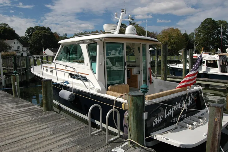 Slide: The Image of 2014 Back Cove 34 boat docked, featuring American flag and scenic marina backdrop. - 11