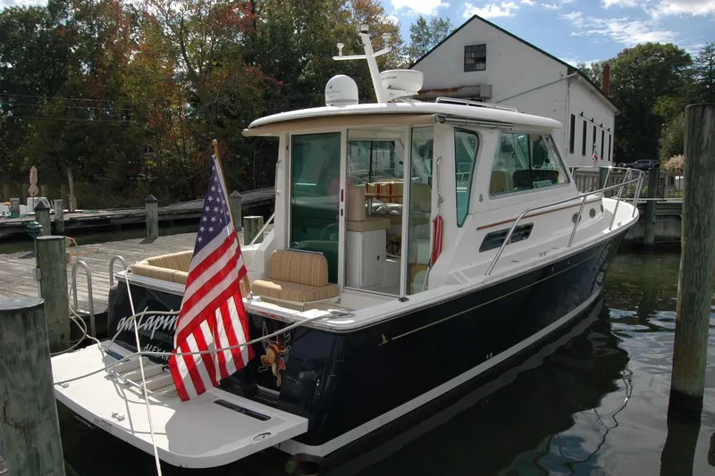 Slide: The Image of 2014 Back Cove 34 boat docked, featuring American flag and elegant design. - 12