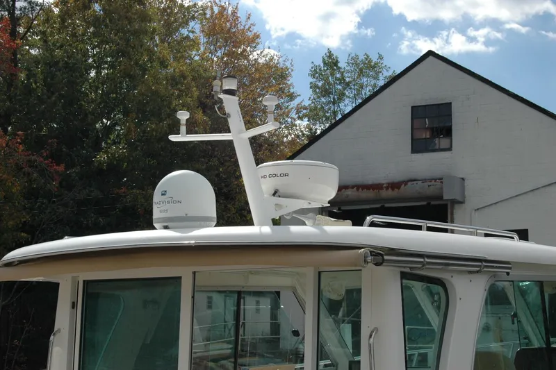 Slide: The Image of 2014 Back Cove 34 boat with radar equipment, docked near a building and trees. - 13