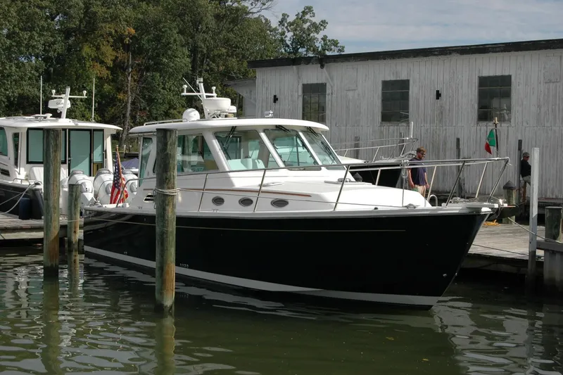 Slide: The Image of 2014 Back Cove 34 boat docked near a wooden building, surrounded by water and trees. - 25