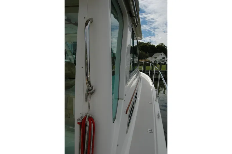 Slide: The Image of 2014 Back Cove 34 boat side view with railing and docked houses in background. - 30