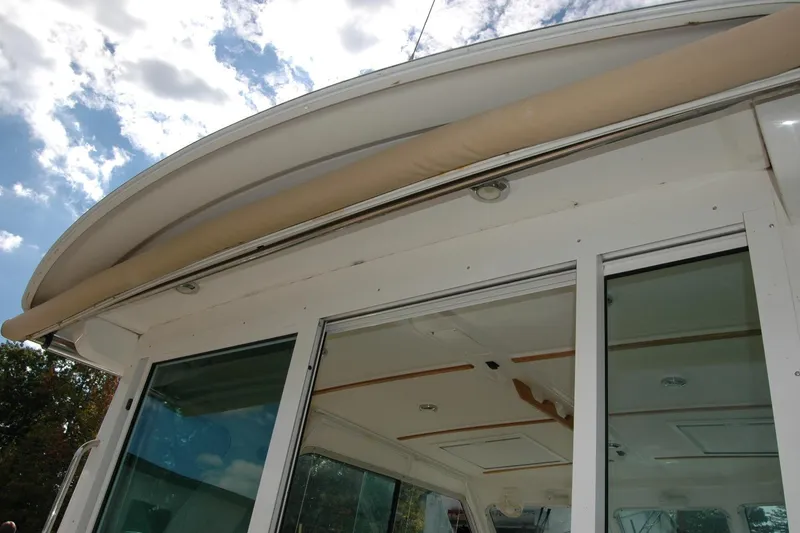 Slide: The Image of 2014 Back Cove 34 boat with sliding glass doors and canopy under a cloudy sky. - 31