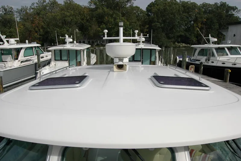 Slide: The Image of 2014 Back Cove 34 boat docked, featuring a sleek white roof and hatches. - 36