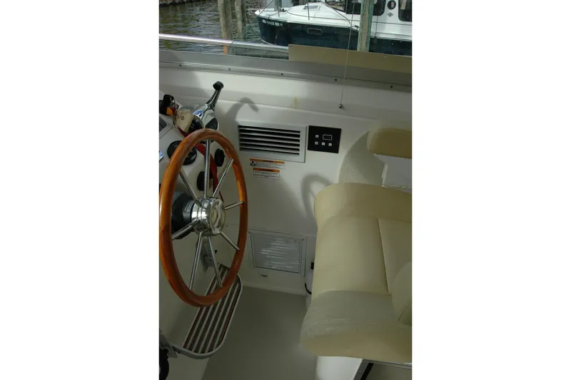 Slide: The Image of 2014 Back Cove 34 boat helm with wooden steering wheel and beige seating. - 60