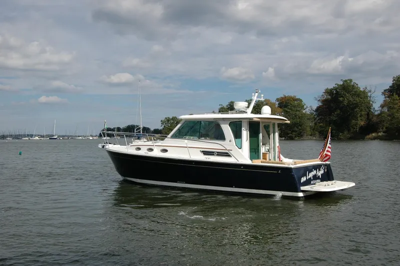 Slide: The Image of 2014 Back Cove 34 boat on calm water with American flag, under cloudy sky. - 7