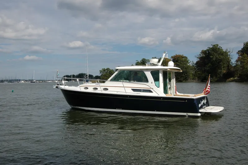 Slide: The Image of 2014 Back Cove 34 boat on calm water, with trees and cloudy sky in background. - 8