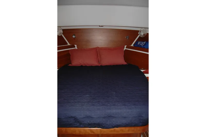 Slide: The Image of Cozy cabin bed in 2014 Back Cove 34 yacht with navy bedding and red pillows. - 84