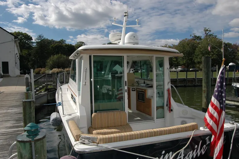 Slide: The Image of 2014 Back Cove 34 boat docked, featuring a cozy seating area and American flag. - 9