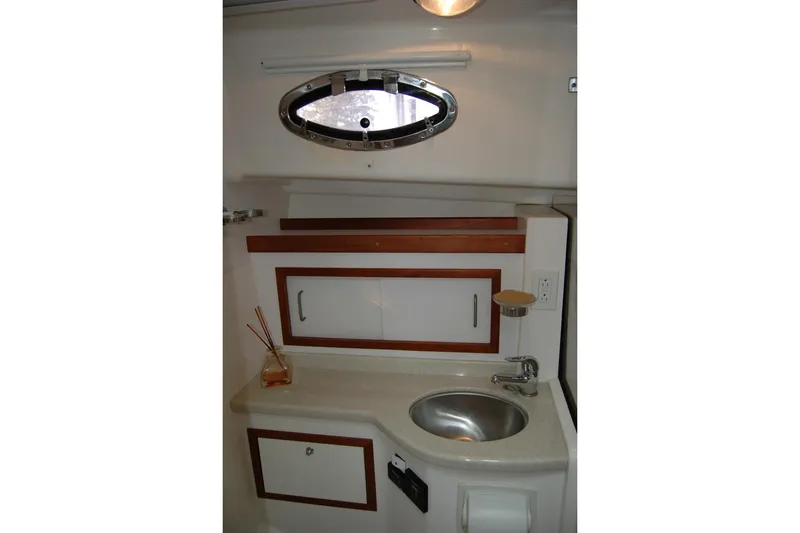 Slide: The Image of 2014 Back Cove 34 yacht bathroom with sink, porthole, and wooden cabinetry. - 96