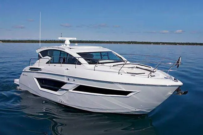 The Image of 2026 Cruisers Yachts 46 Cantius on serene water near waterfront homes. - 1