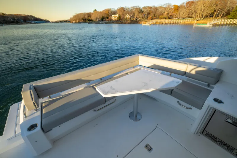 Slide: The Image of Luxurious 2026 Cruisers Yachts 46 Cantius deck with seating and table, overlooking serene water. - 13