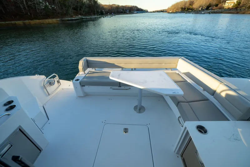 Slide: The Image of 2026 Cruisers Yachts 46 Cantius deck with seating and table, overlooking serene waterway. - 50