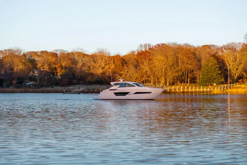 Slide: The Image of 2026 Cruisers Yachts 46 Cantius on serene lake with autumn trees in background. - 52