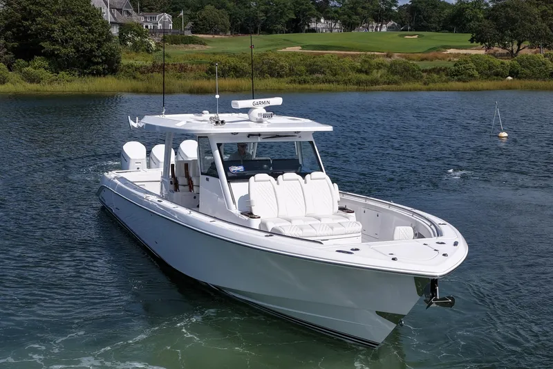 Slide: The Image of 2026 Everglades 455 Center Console boat on calm water near a lush shoreline. - 3