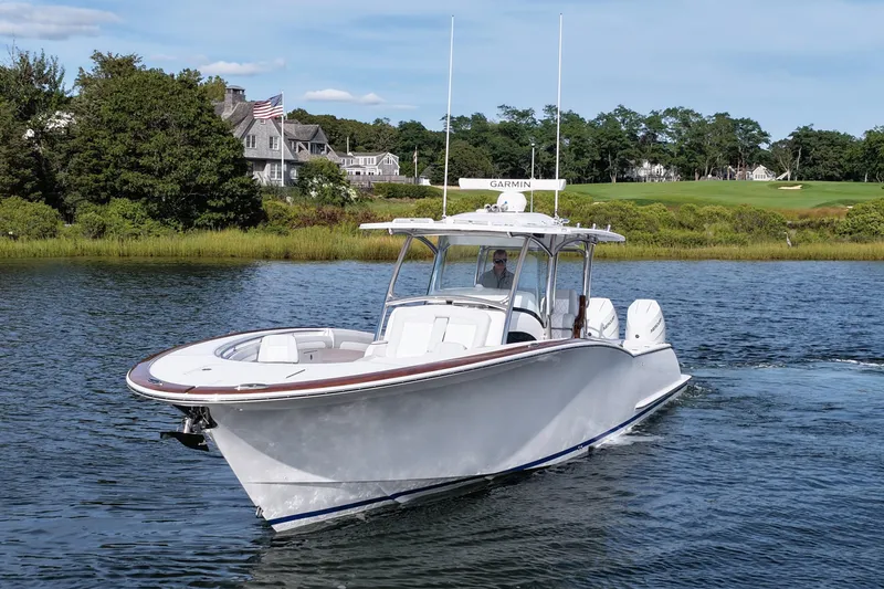 Slide: The Image of 2026 Mag Bay 38 boat cruising on a scenic lake with lush greenery. - 11