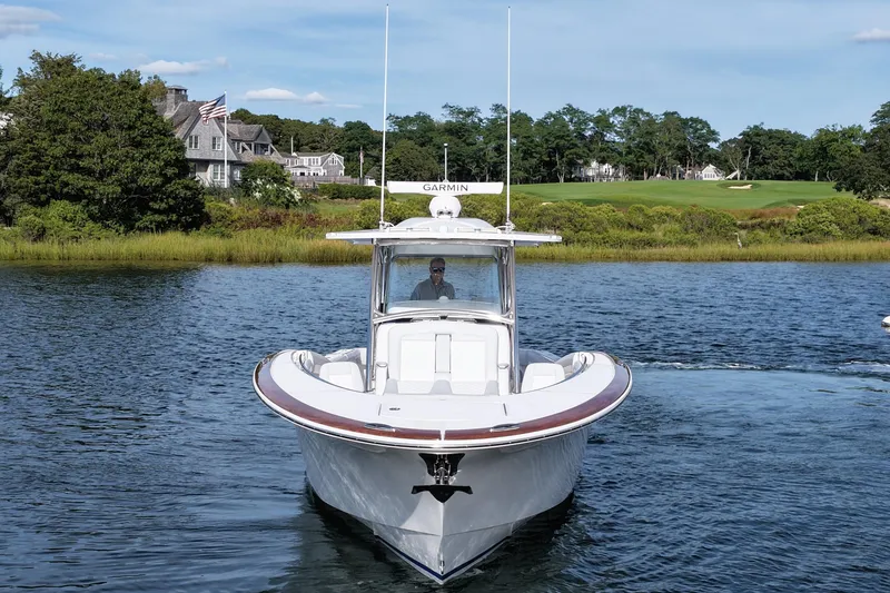 Slide: The Image of 2026 Mag Bay 38 boat cruising on a scenic lake with houses in the background. - 12