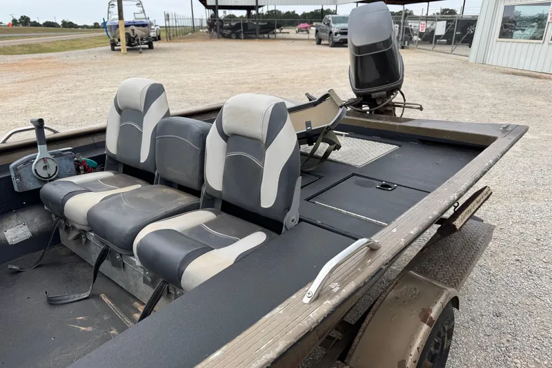 Slide: The Image of 2000 Express X51 boat interior with three seats and motor, parked on gravel. - 6