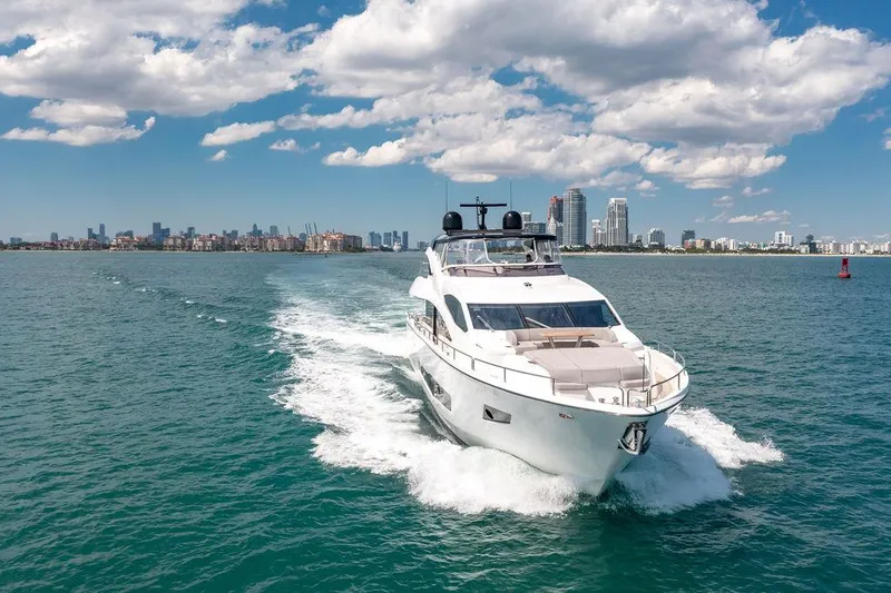 Slide: The Image of Sunseeker 86 Yacht 2021 cruising on open water with city skyline in background. - 10