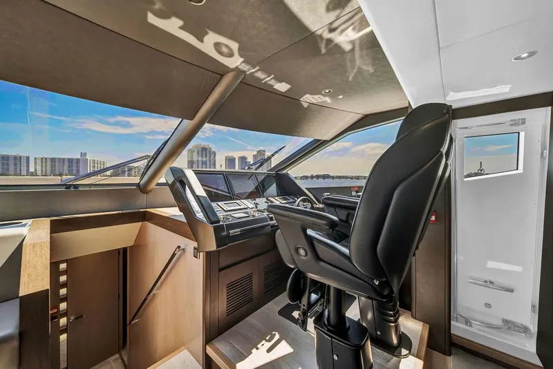 Slide: The Image of Pilot seat and controls inside 2021 Sunseeker 86 Yacht, with city skyline view. - 26