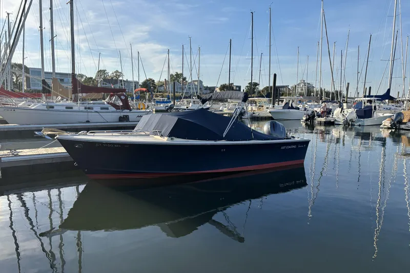 The Image of 2015 Rossiter 23 boat docked in a marina with sailboats in the background. - 0