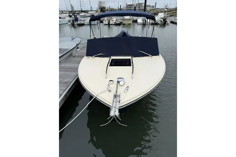 Slide: The Image of 2015 Rossiter 23 boat docked in a marina with sailboats in the background. - 2