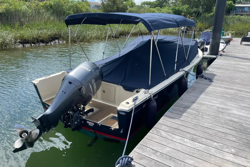 Slide: The Image of 2015 Rossiter 23 boat with Yamaha engine, docked, featuring tan seating and American flag. - 29
