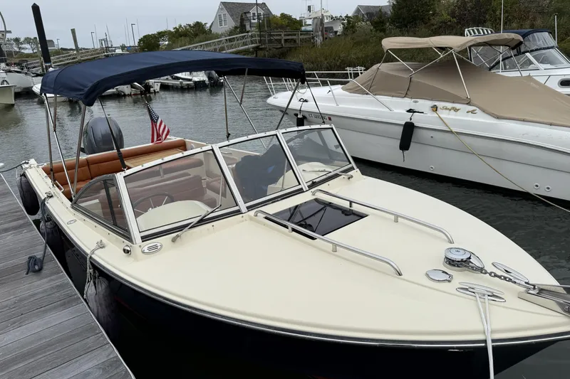 Slide: The Image of 2015 Rossiter 23 boat docked, featuring a navy canopy and American flag. - 31