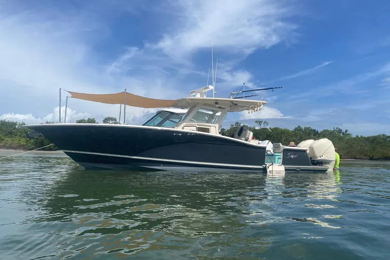 Slide: The Image of 2019 Scout 320 LXF boat anchored on calm water under a clear blue sky. - 33