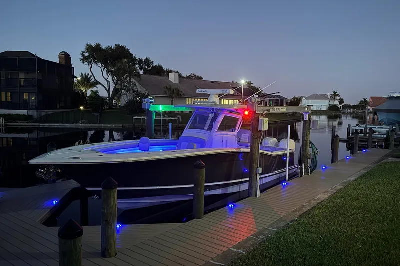 Slide: The Image of 2019 Scout 320 LXF boat docked at night with vibrant LED lights. - 34