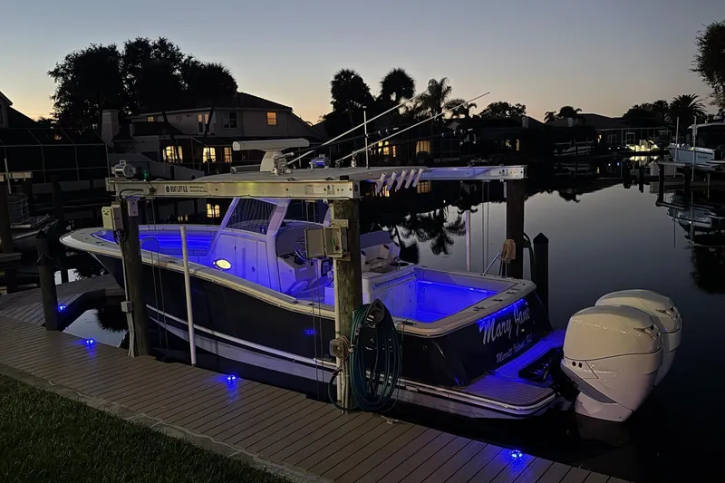 Slide: The Image of 2019 Scout 320 LXF boat docked at sunset with blue interior lights. - 35