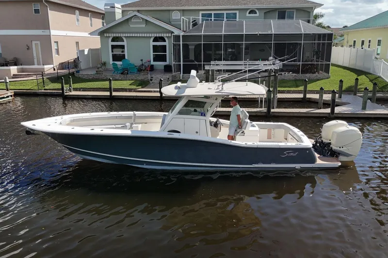 Slide: The Image of 2019 Scout 320 LXF boat docked near waterfront homes. - 6