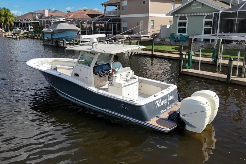 Slide: The Image of 2019 Scout 320 LXF boat cruising in a residential canal. - 7