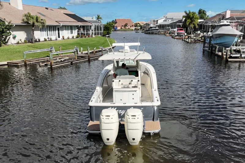Slide: The Image of 2019 Scout 320 LXF boat navigating a residential canal with waterfront homes. - 8