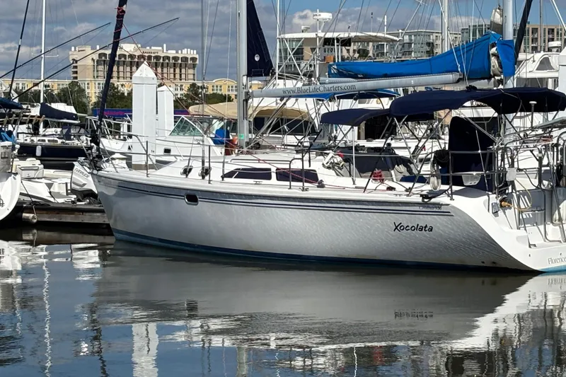 Slide: The Image of 2006 Catalina 320 sailboat docked in a marina, reflecting on calm water. - 2