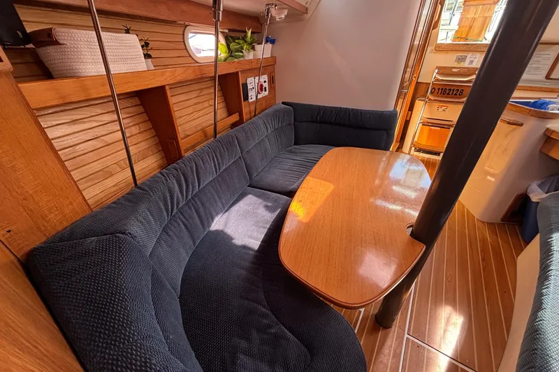 Slide: The Image of Cozy interior of 2006 Catalina 320 sailboat with wooden table and blue seating. - 23