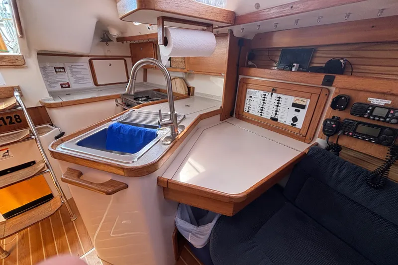Slide: The Image of Interior of a 2006 Catalina 320 sailboat featuring a compact kitchen and control panel. - 28