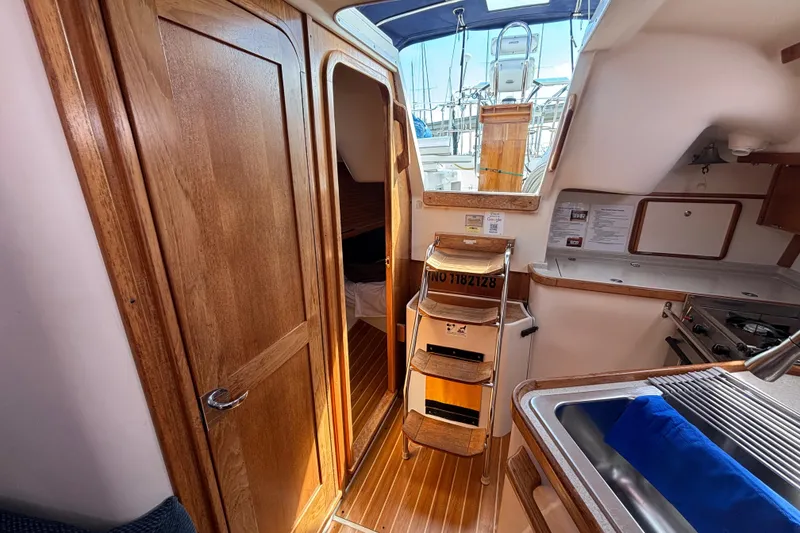 Slide: The Image of Interior of 2006 Catalina 320 sailboat with wooden cabinetry and compact kitchen area. - 29