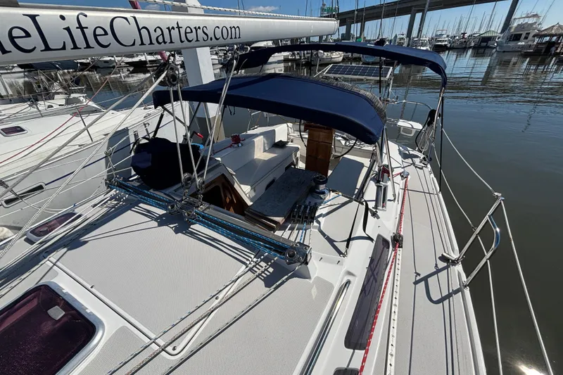 Slide: The Image of 2006 Catalina 320 sailboat docked at marina, featuring blue canopy and clean deck. - 8