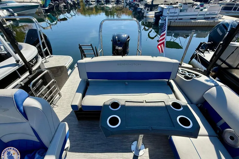 Slide: The Image of 2021 Bennington 22 LSB pontoon boat interior with seating and table, docked at marina. - 11