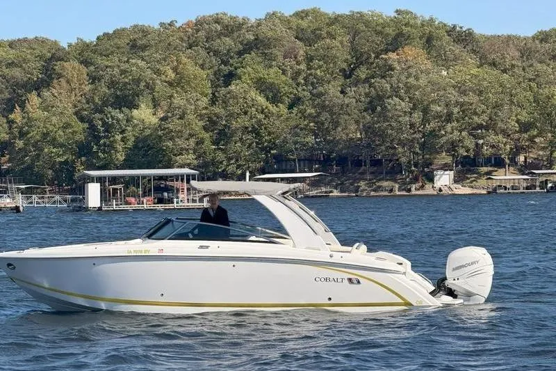 Slide: The Image of 2022 Cobalt 30SC Outboard boat cruising on a lake with wooded shoreline. - 2