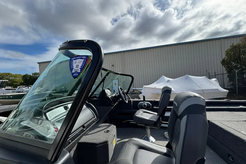 Slide: The Image of 2020 Lund 1675 Adventure Sport boat interior with windshield and seating, under cloudy sky. - 13