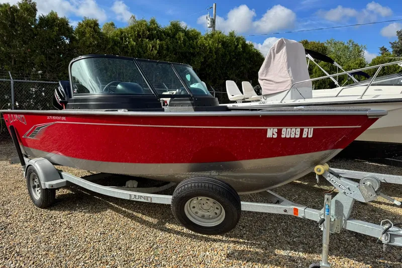 Slide: The Image of 2020 Lund 1675 Adventure Sport boat in red on a trailer, parked outdoors. - 2