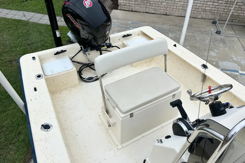 Slide: The Image of Jones Brothers 22 Bateau 2000 boat interior with seating and motor, parked on concrete. - 11